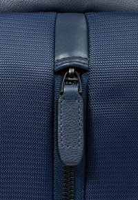Borsa con zip in tessuto blu navy con nylon testurizzato, dettagli in pelle e una pratica chiusura lampo liscia. Caratterizzata da un design pulito e strutturato.
