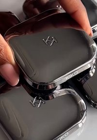 Svart kompakt sminkfodral med blank finish, med en upphöjd logotyp "KIKO" och en slank, rundad design. Slät yta.