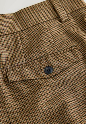 Pantaloni a quadri marroni e neri con una texture liscia, dotati di una tasca posteriore e una chiusura a bottone nera. Design su misura con vita strutturata.