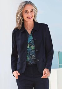 Navyblauwe jas met een kraag en zes knopen, gecombineerd met een kleurrijke gebloemde blouse. Slim fit, geweven stof. Twee voorzakken.