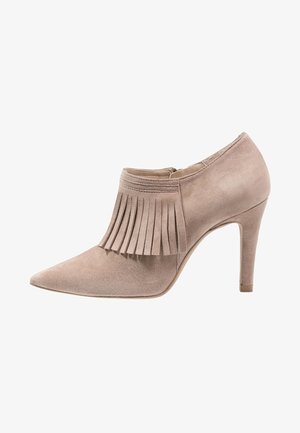 Zapato de tacón alto de ante beige con punta puntiaguda y detalles de flecos en la parte delantera, diseño a la altura del tobillo y cremallera lateral.