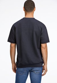 Felpa a maniche corte blu navy con vestibilità rilassata, polsini e fondoschiena a costine, realizzata in un materiale morbido e testurizzato.