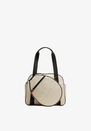 Bolsa tote beige y negra con correas negras anchas y bolsillo delantero redondeado que muestra el logo "lululemon" en letras blancas.