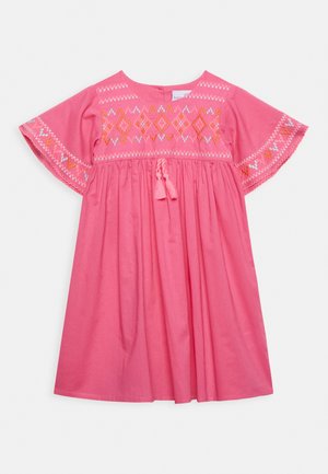 Roze katoenen jurk met korte vleugelachtige mouwen, geborduurde geometrische patronen in oranje en wit, en een ceintuurtje met kwastjes in de taille.