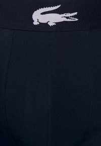 Navy bomullsblandning boxershorts med en bred elastisk midja som har en vit Lacoste-krokodil-logga och en slät textur.