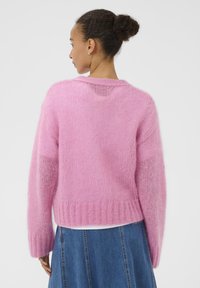 Rosa, flauschiger Pullover aus Mohair mit rundem Ausschnitt, geripptem Saum, überschnittenen Schultern und durchscheinenden Einsatzdetails.