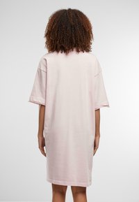 Rochie-ți cu mânecă scurtă, de culoare roz pal, oversized, cu o textură moale, având un croi simplu și drept și un guler rotund.