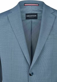 Jasnoniebieska marynarka z wyciętymi klapami, pojedynczym ciemnym guzikiem, kieszenią na piersi oraz wewnętrzną podszewką z delikatnym wzorem i metką "HECHTER PARIS".