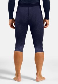 Marineblaue Leggings mit strukturiertem Oberflächen, ausgestattet mit einem figurbetonten Design, das bis zur Mitte der Wade reicht. Glatter Bund und subtiler Farbverlauf von dunkel zu hell.