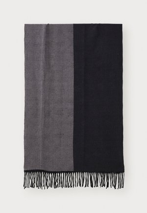 Plaid de canapé noir et gris avec un tissu texturé, présentant un design divisé et des bords frangés.