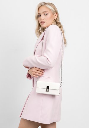 Witte handtas met een gestructureerde afwerking, rechthoekige vorm en een zilveren kettingriem. Beschikt over een metallic sluiting en wordt gedragen met een pastelroze blazer.