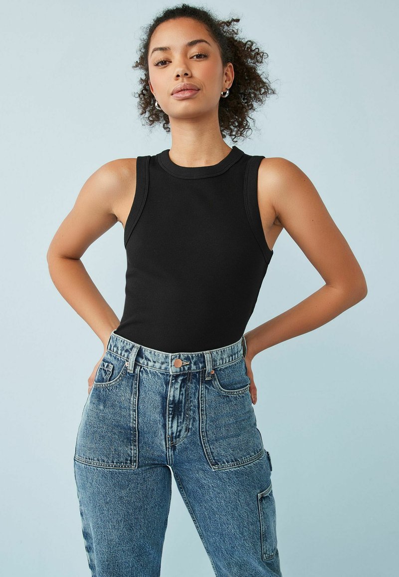 Sort ribbet tanktop med en høj halsudskæring, parret med højtaljede, lys blå denimjeans med flere lommer og en afslappet pasform.