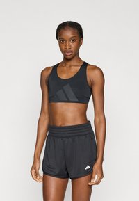 Μαύρο αθλητικό cropped τοπ με υφή δίχτυ και λογότυπο, σε συνδυασμό με μαύρο σορτς ψηλόμεσο με ελαστική μέση και λεπτομέρεια λογότυπου.