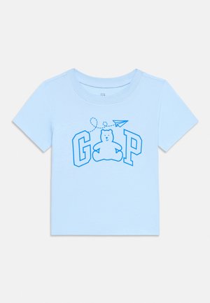 Chemise à manches courtes bleu clair pour tout-petit avec un ours en peluche bleu, un avion en papier et les lettres G et P sur le devant.