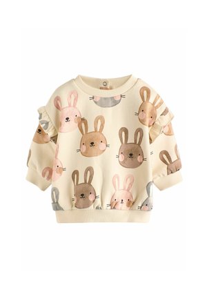 Ljus krämfärgad sweatshirt med ett mönster av illustrerade kaniner i nyanser av brunt, rosa och grått. Volangärmarna ger textur och detalj.