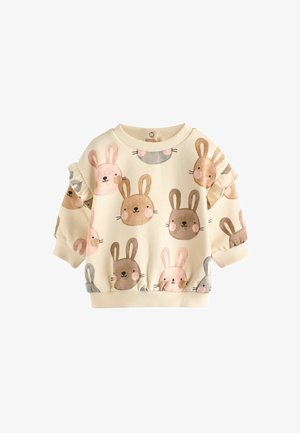 Világos krémszínű pulóver, amelyet barna, rózsaszín és szürke árnyalatú illusztrált nyulak mintázata díszít. A fodros ujjak textúrát és részletességet adnak.