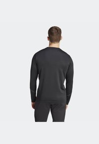 Black long-sleeve athletic shirt with a crew neckline, smooth texture, and reflective stitching accents. Designed for active wear.