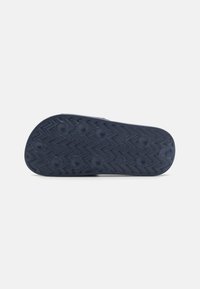 Suela de zapato de goma azul con un patrón en zigzag y detalles de agarre circular. Plana, con texturas variadas para mejorar la tracción.