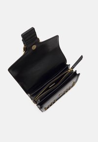 Svart läderplånbok med slät yta, prydd med guldfärgad hårdvara, zippered fack och dekorativa nitar på ena sidan.