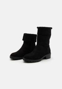 Bottines en suède noir avec un col replié, un intérieur texturé et une semelle en caoutchouc robuste. Fini lisse, bout rond et talon de hauteur moyenne.