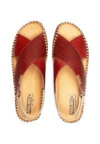 Sandalias de cuero rojo con diseño de tiras cruzadas, detalles perforados, plantilla beige y borde trenzado. Logo de la marca visible en la plantilla.