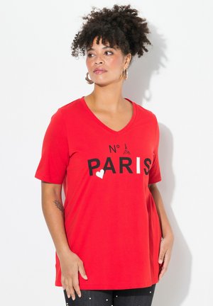 T-shirt rouge en coton avec encolure en V, portant le texte noir "N° PARIS" et un graphique en forme de cœur, à manches courtes et coupe décontractée.