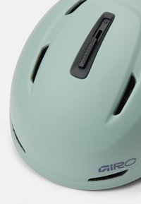 Jasnozielony kask rowerowy z otworami wentylacyjnymi, czarnym pokrętłem regulacyjnym i matowym wykończeniem. Logo umieszczone po boku.