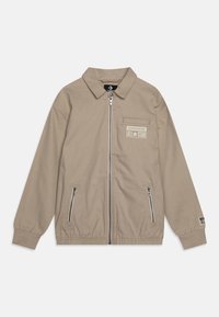 Jasnobeżowa kurtka zapinana na zamek z kołnierzykiem, elastycznymi mankietami, dwiema kieszeniami na zamek oraz nadrukiem z przodu przedstawiającym "Converse All Star."