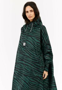 Zielono-czarny ponczo w paski zebry z kapturem, napami i bocznymi kieszeniami, wykonane z lekkiego, wodoodpornego materiału.