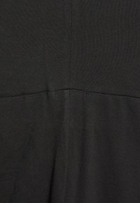 Sort, tekstureret stof med en glat overflade og en let glans. Viser en vandret søm i midten, der antyder beklædningskonstruktion.