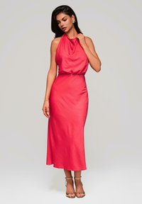 Robe rouge à col halter, avec un décolleté drapé, une silhouette épurée et une longueur aux genoux. Fabriquée dans un tissu lisse avec des détails texturels subtils.