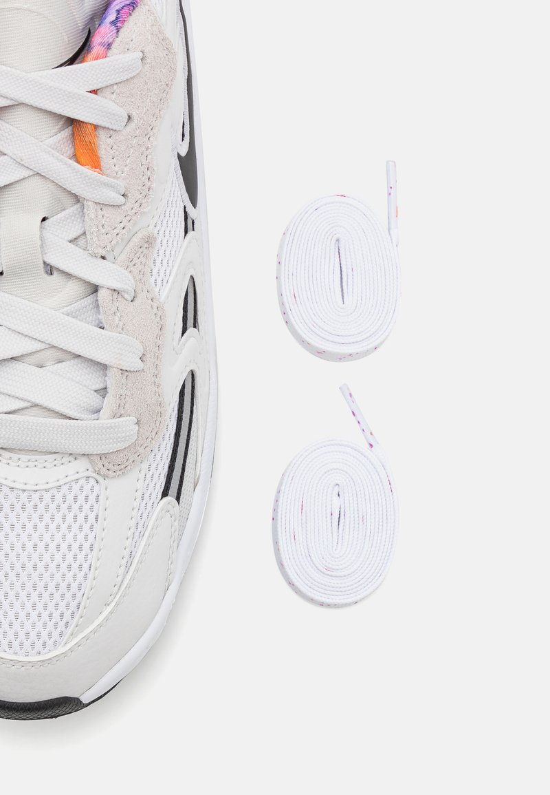 Bamba de malla blanca y gris con acentos de ante gris claro y dos cordones blancos enrollados con pequeñas motas de color sobre un fondo blanco.