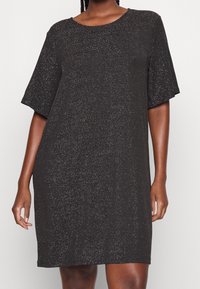 Schwarzes Kleid mit lockerer Passform, kurzen Ärmeln, runder Halslinie und einem strukturierten Stoff, der dezente metallic-fäden enthält.