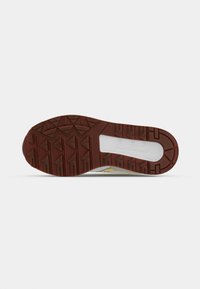 Brown rubber outsole with a textured pattern, featuring triangular lugs for traction. White midsole contrasts with the outsole.