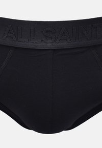 Culottes en coton noir avec une ceinture texturée arborant le nom de la marque gravé "ALLSAINTS". Tissu lisse avec un design ajusté.