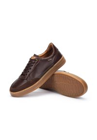 Sneaker in pelle marrone con colletto imbottito e design con lacci. Presentano dettagli perforati e una suola in gomma testurizzata.