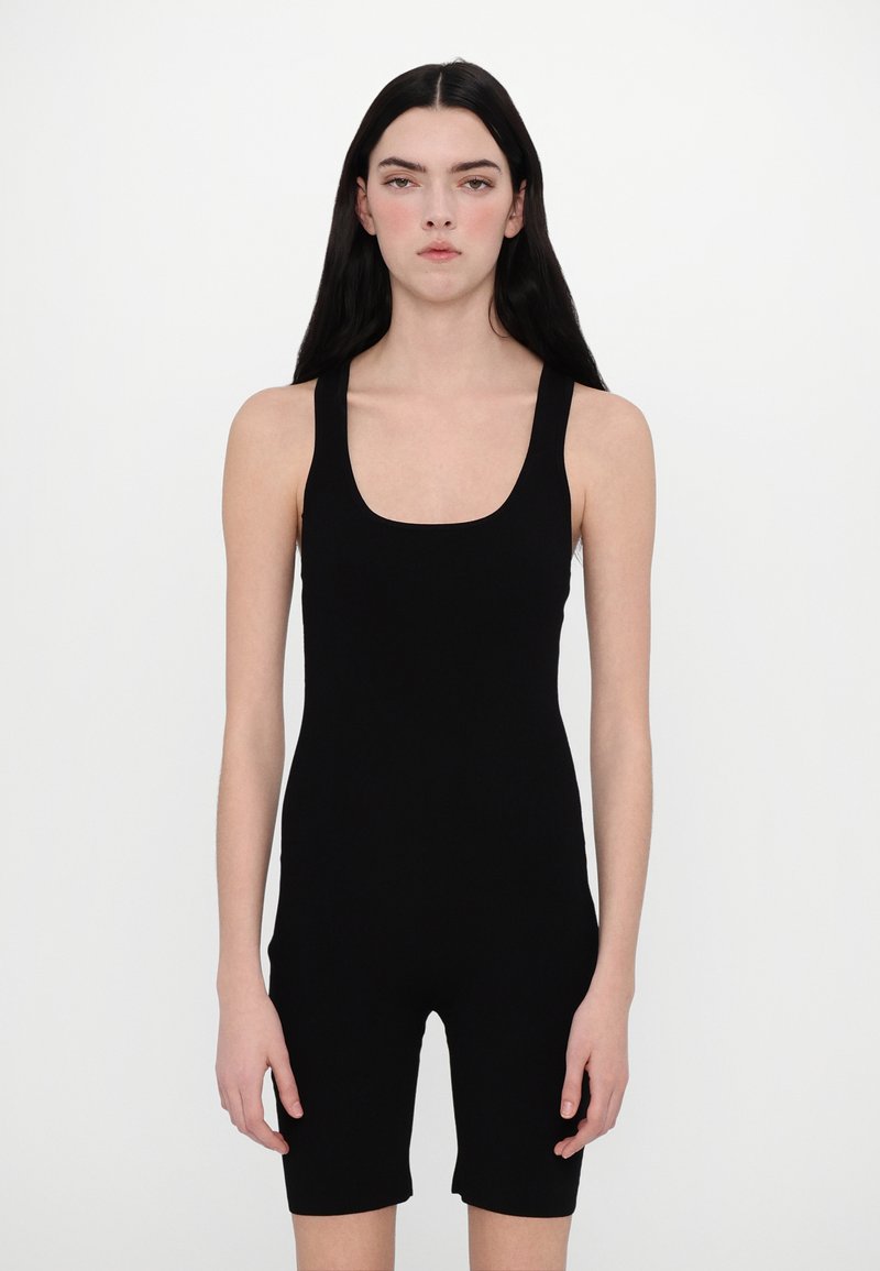 Bodysuit sans manches noir avec un décolleté en U, au design ajusté et à la jambe style short. Fabriqué en matériau lisse et élastique. Aspect minimaliste.