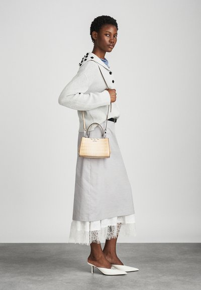 Light gray sweater with black buttons, gray skirt with white lace hem, beige textured handbag, and white pointed heels.