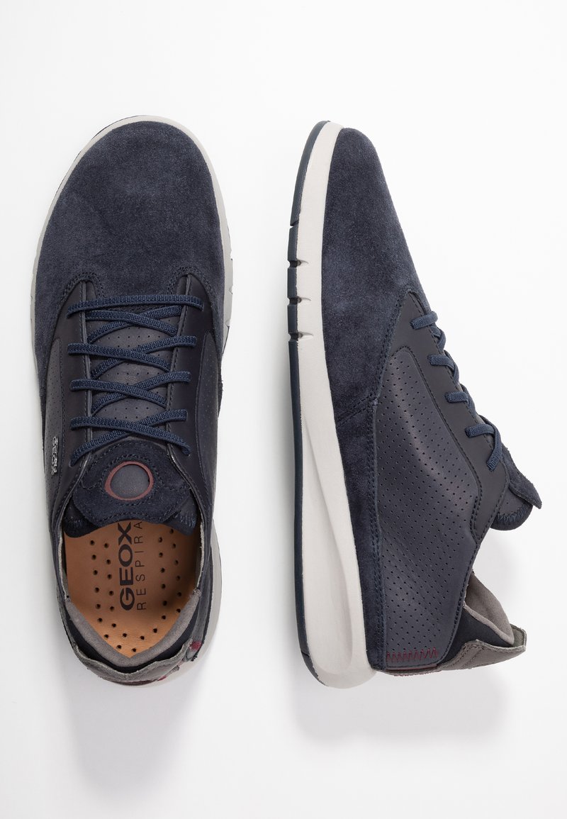 Baskets en suède bleu marine pour hommes avec des accents en cuir lisse, des panneaux latéraux perforés, des œillets ronds et une semelle rembourrée.