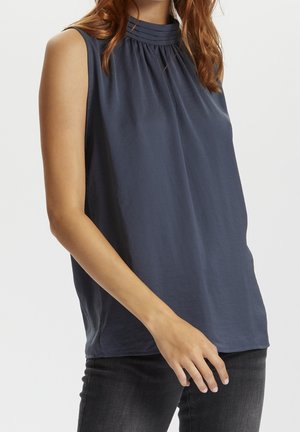 Sleeveless dark gray blouse with pleated high neckline worn with black jeans on model against white background.