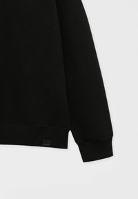 Svart sweatshirt med långa ärmar, ribbad mudd och en liten logotyp i nederkant. Mjuk och texturerad tyg.