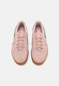 Helle rosa Wildleder-Sneaker mit runden Zehen, farblich abgestimmten Schnürsenkeln und einer Gummisohle; mit goldenen Akzenten und kontrastierenden marineblauen Seitenstreifen.