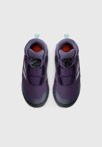 Lila Wanderschuhe mit strukturierter Oberfläche, Boa-Schnürsystem, schwarzen Sohlen und rotem Innenbereich. Verfügt über eine hellblaue Zuglasche.