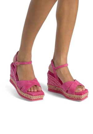 Sandali con tacco a zeppa in suede rosa con cinturini incrociati, caratterizzati da una base in espadrillas intrecciata e dettagli decorativi in corda sulla suola.