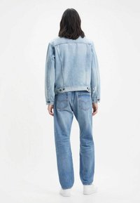 Jasnoniebieska kurtka dżinsowa o lekko zniszczonym fasonie, w komplecie z pasującymi jasnoniebieskimi dżinsami. Elementy charakterystyczne to tylne kieszenie i guziki.