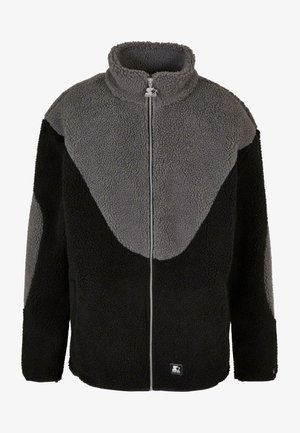 Melnā un pelēkā fleecē jaka ar augstu apkakli, rāvējslēdzēju un krāsu bloku dizainu. Mīksta tekstūra ar logo akcentu apakšmalā.