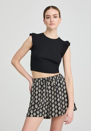 Top corto nero con maniche arricciate abbinato a pantaloni corti neri e crema a motivo, con vita regolabile e vestibilità comoda.