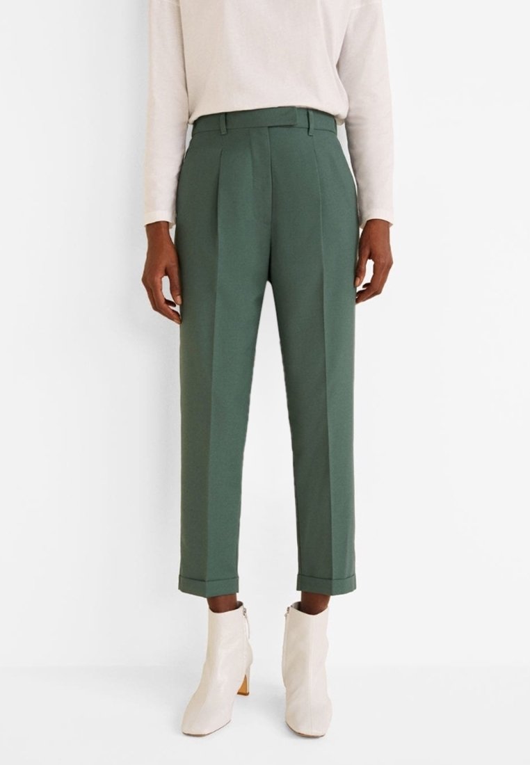 Groene geplooide broeken van een zachte stof, met een hoge taille en cropped lengte, gecombineerd met witte hoge enkelschoenen.
