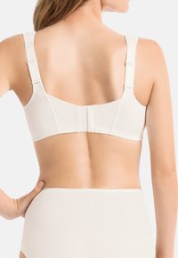 Biały stanik z regulowanymi ramiączkami, zapięciem z tyłu i gładką fakturą, zaprojektowany z myślą o komforcie i wsparciu. Widok od tyłu pokazujący ramiączka i pas.