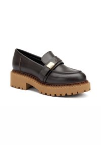 Mocassino in pelle nera con suola piatta chunky beige, caratterizzato da una fascia orizzontale e dettagli in tonalità oro. Texture liscia.